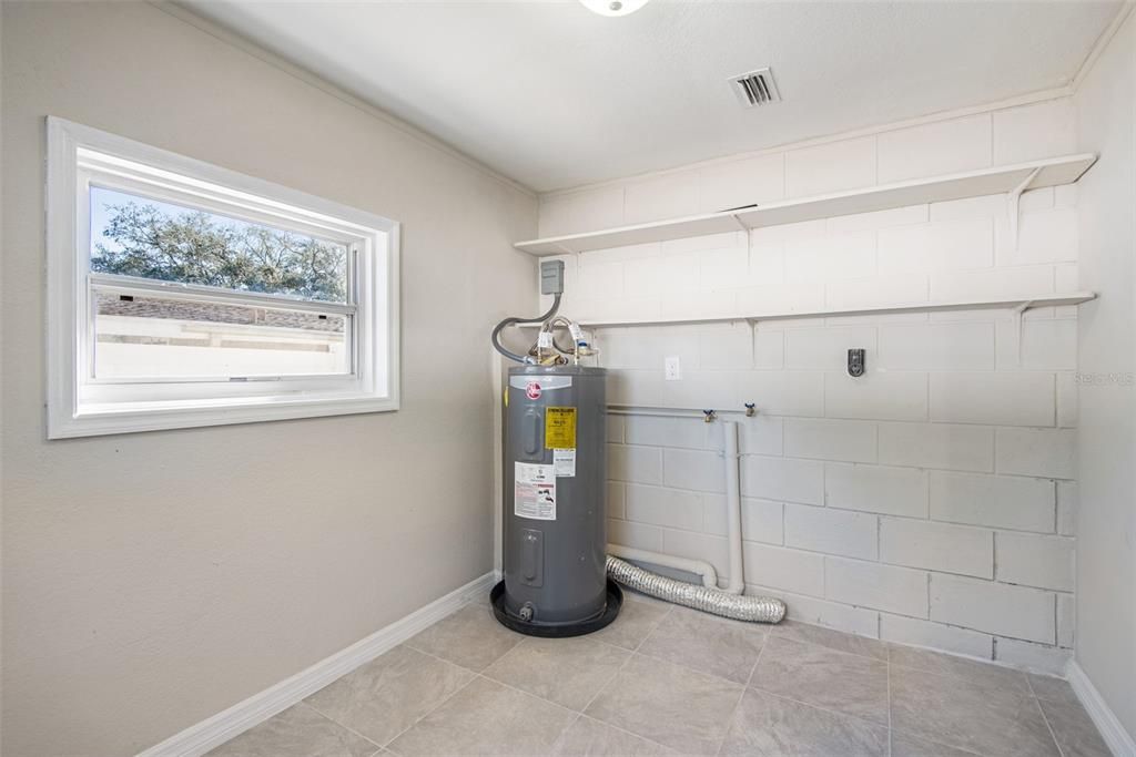 Step in to the laundry and storage room with space for a washer and dryer and room to hang clothes. Water heater located here. Room for a pantry. Nice large bright space.