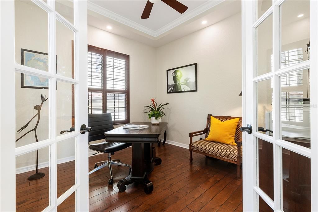 Office/Den with wood flooring, French doors and crown molding.