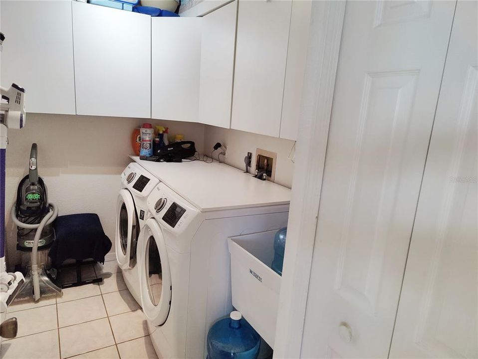 separated laundry room, with samsung front loading washer and dryer, sink, pantry, storage cabinets