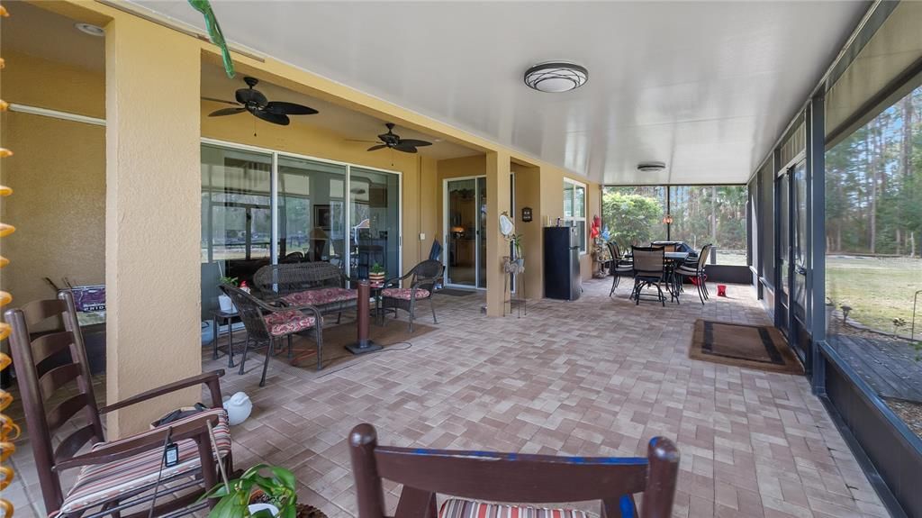 Large covered screened paver patio in the back of home