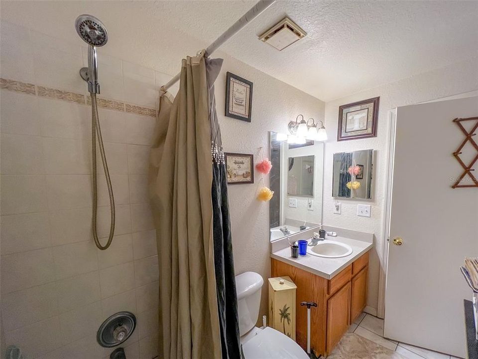 upstairs bathroom with tub/shower combo, handheld shower head with hose, under-sink storage cabinet