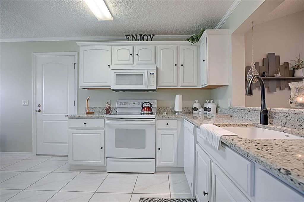 The meals will be fun to prepare in this white kitchen.  The granite counter tops add to the beauty of the room.