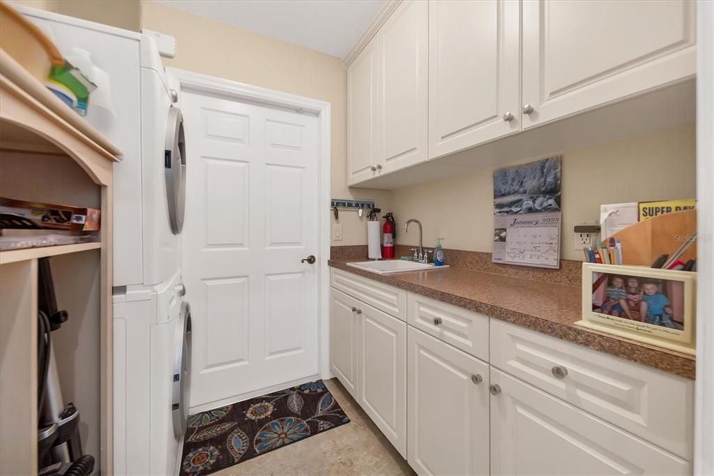 utility room with sink, plenty of cabinetry and exit to 3 car garage
