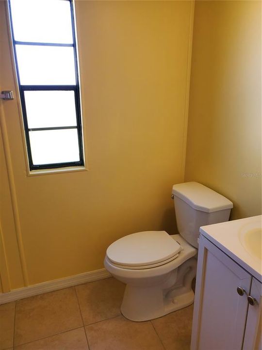 Toilet and basin in main tiled bathroom.