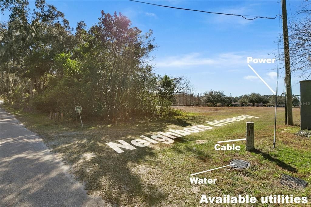 Notice the neighbors public water meter, cable/internet hub and power pole. The new home owner will choose where to put it's driveway within the 150' of road frontage.