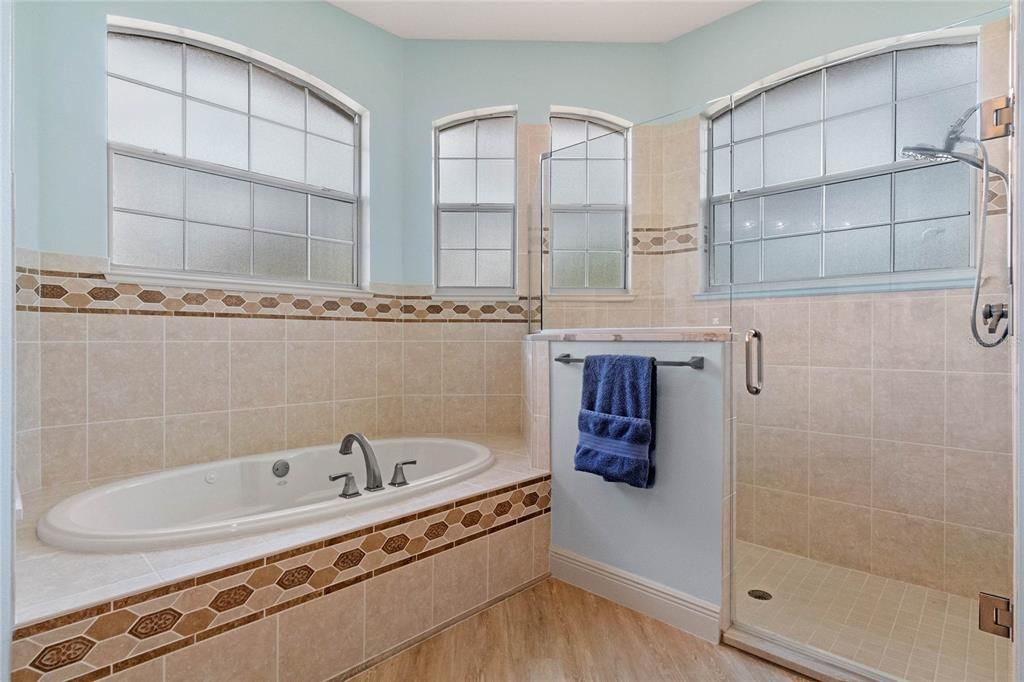 Master bathroom showing a separate tub & shower recess on  tiled floors.