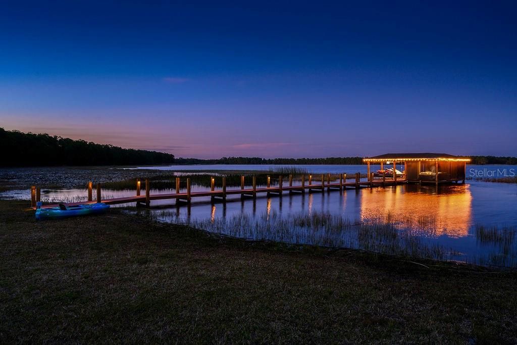 Dock and boathouse at dusk with lights on