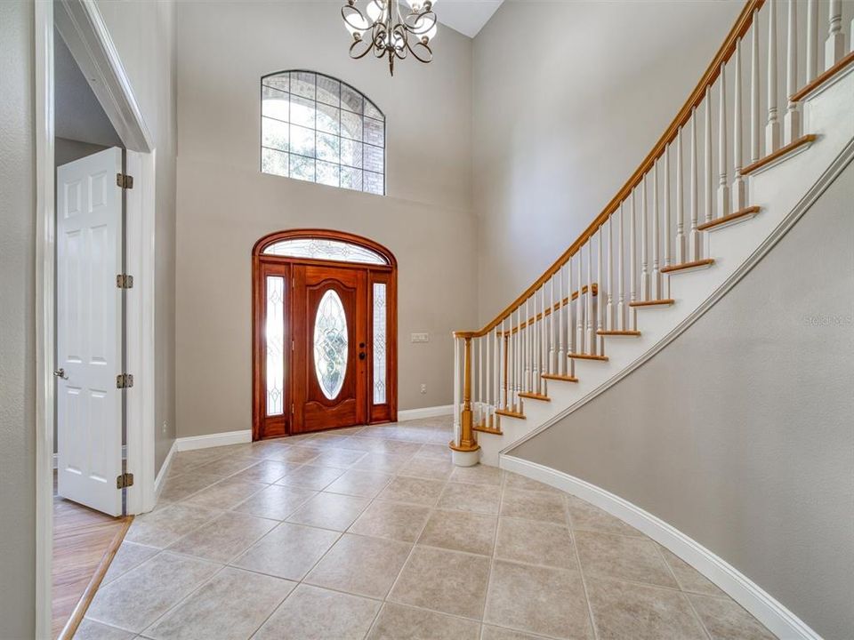 Enter the Foyer with Soaring Ceilings, Gleaming Porcelain Tile Floors and a Dramatic Staircase