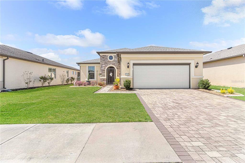 Paver driveway, stone accents on front of home.