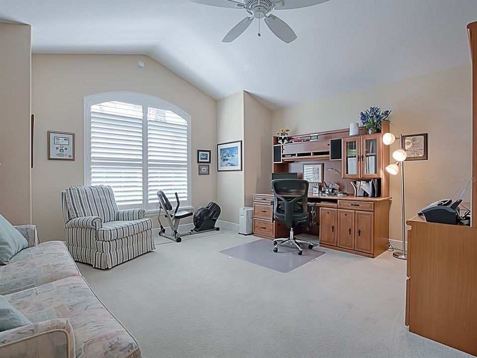 SPACIOUS FRONT GUEST ROOM BEING USED AS AN OFFICE/DEN WITH VAULTED CEILINGS WITH CEILIING FAN AND PLANTATION SHUTTERS!