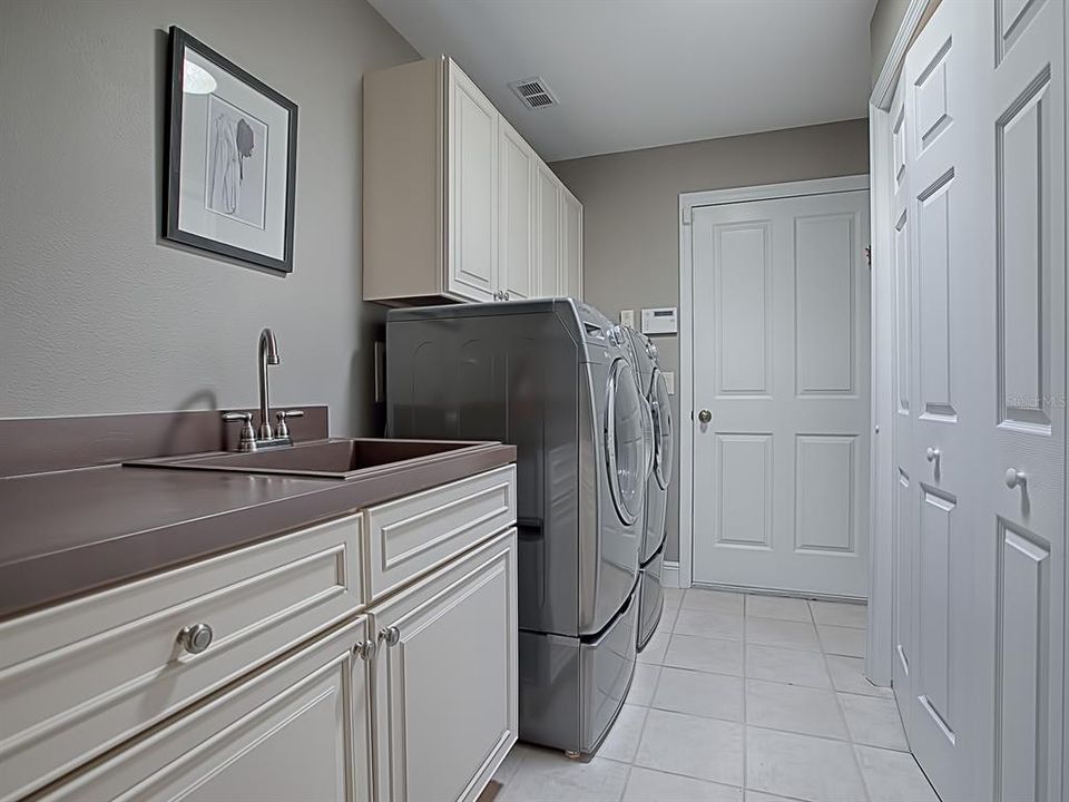 SPACIOUS LAUNDRY ROOM WITH FRONT LOAD WASHER AND DRYER ON PEDESTALS, BUILT IN SINK AND LOTS OF EXTRA CABINETS AND CLOSET SPACE!  THE DOOR LEADS TO YOUR 2 CAR AND GOLF CART GARAGE!