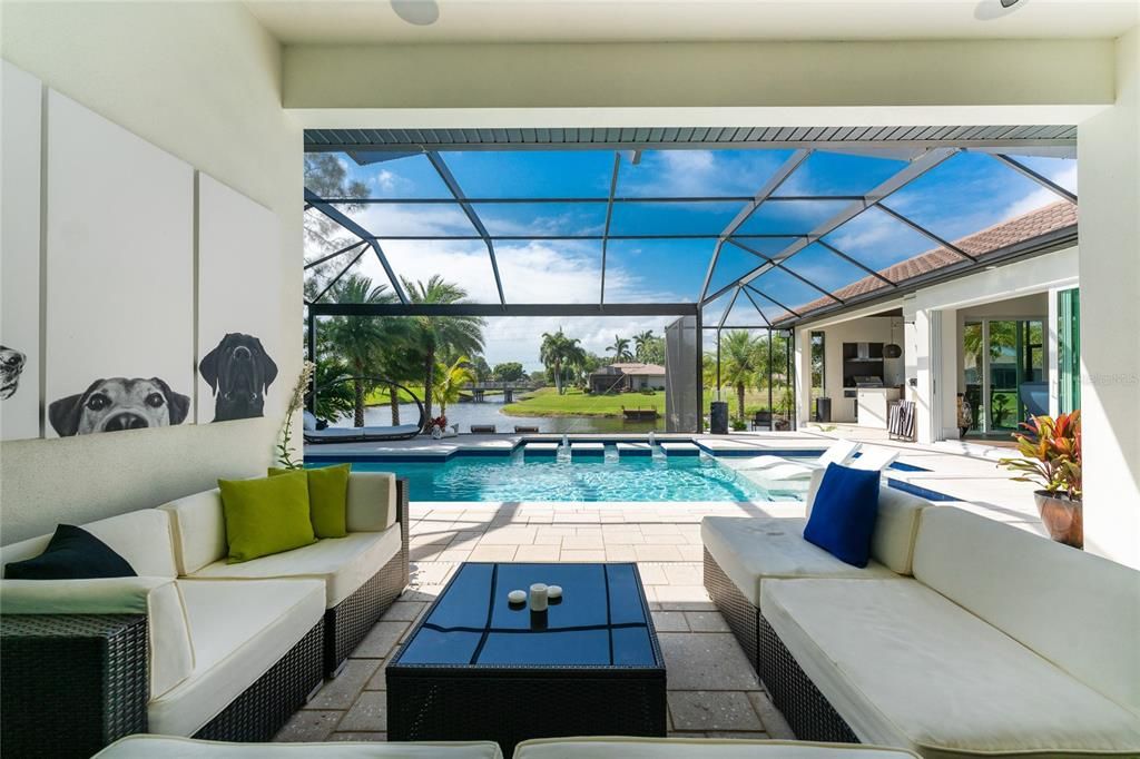 An extra tall cathedral-roof pool cage with clear view screening maximizes the view of the intersecting canal.  Fuss free furniture is placed to encourage leisurely conversation.