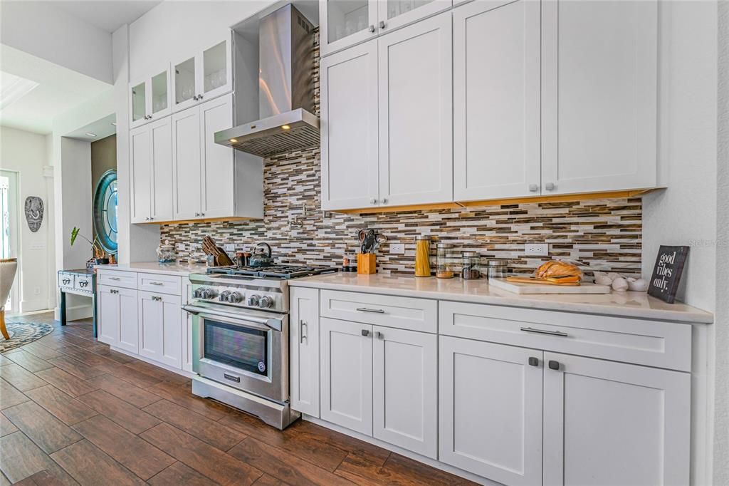 The kitchen offers 42" soft-close cabinets including full upper cabinets with glass doors, a wine rack, open shelves, and a coffee station.