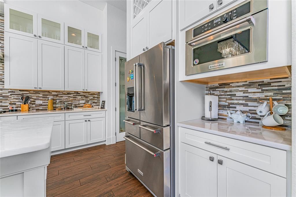 The multi-door refrigerator offers soft close drawers and herb storage, and there is a space saving microwave with a pull-down door.  A thoughtfully chosen glass tile backsplash adds visual interest.