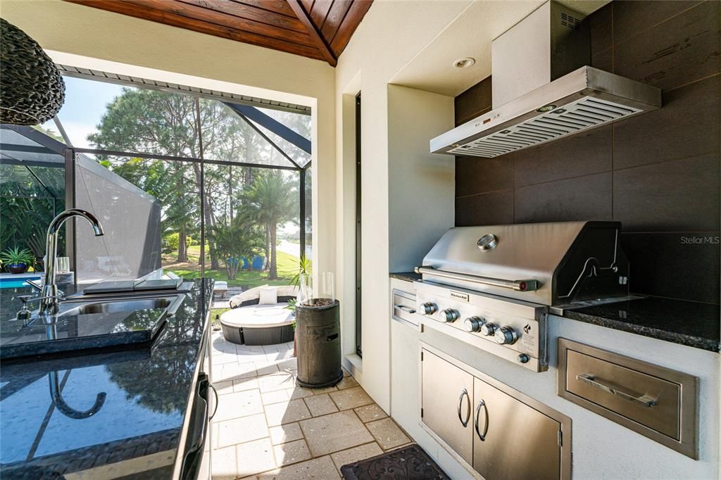 A built-in Kitchen Aid grill with extra burners, a rotisserie, an exhaust hood  w/a tile backsplash, and an exterior propane gas hook-up make food prep a pleasure.