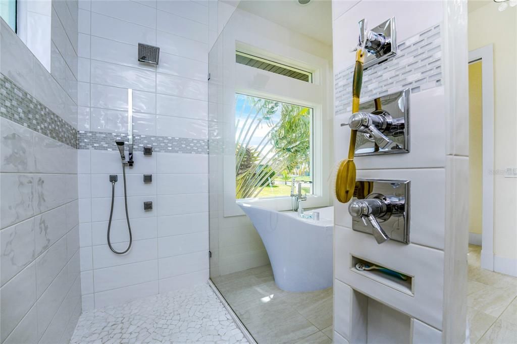 Highlights in the walk-in shower include a Hansgroehe rain shower head, body sprays, and a handheld sprayer.