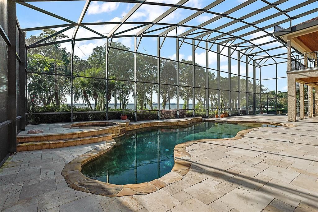 Resort style travertine pool deck with a sparkling pool and spa