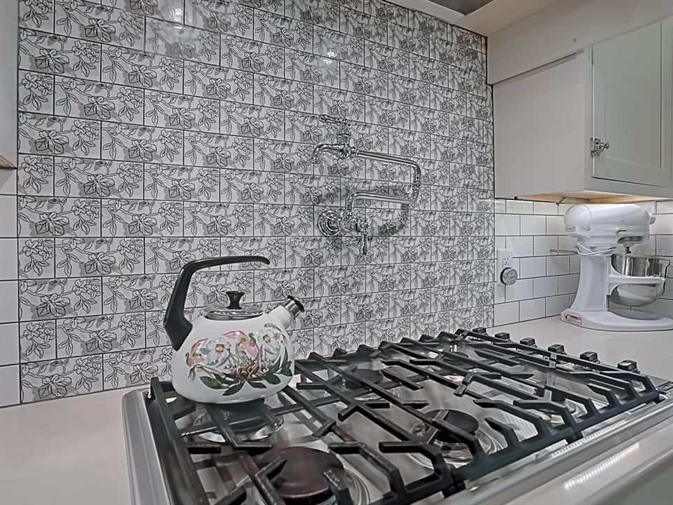 SIX BURNER GAS COOKTOP WITH VENT HOOD, DECORATIVE TILE BACKSPLASH AND A CONVENIENT POT FILLER FAUCET MOUNTED OVER THE STOVE!