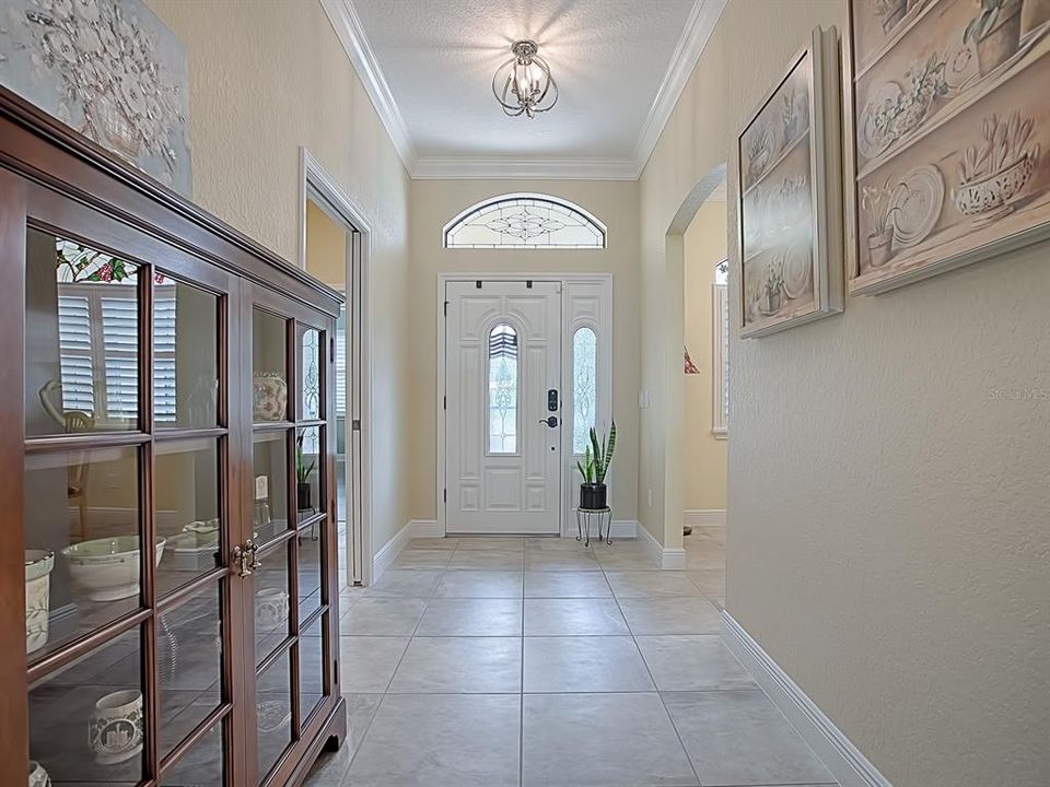 WHAT A GRAND FOYER! CUSTOM LIGHT FIXTURES THROUGHOUT THE HOME - LOVELY TILE FLOORING! THE POCKET DOOR TO THE RIGHT WHEN YOU ENTER LEADS TO THE GUEST ROOMS AND GUEST BATH!