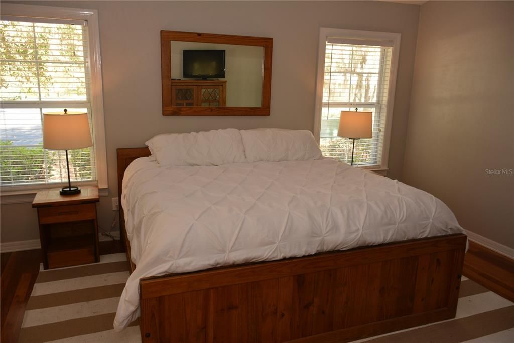 Light and bright spacious master bedroom with hardwood floors, vaulted ceilings, large walk-in closet and French door access to the screened porch