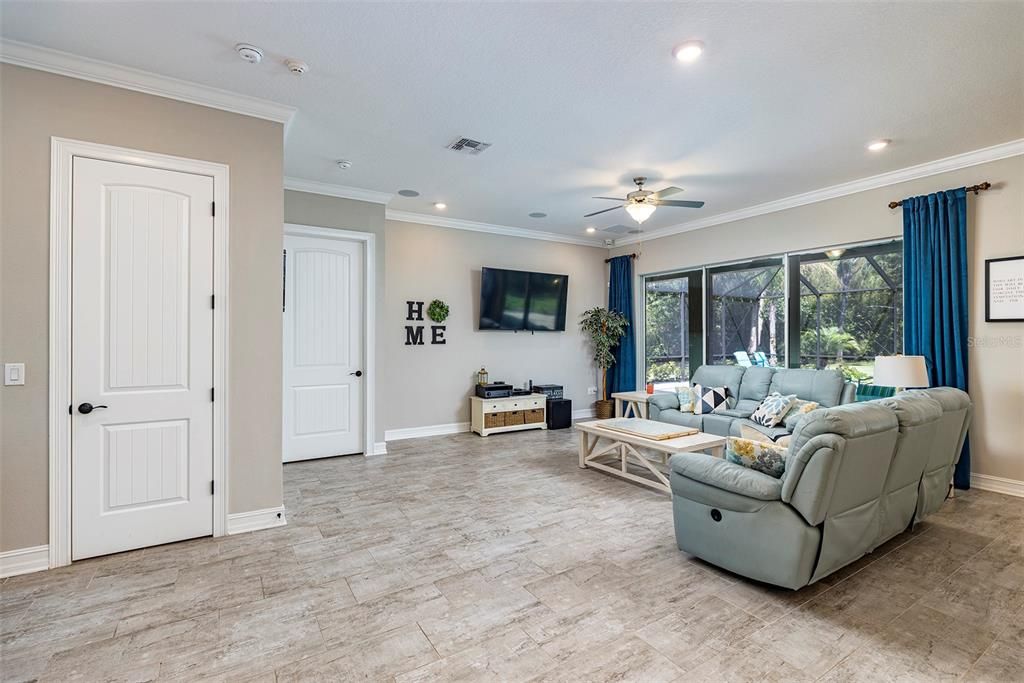 Great room has high ceilings, crown molding and sliders leading out to the expansive pool and screened lanai.