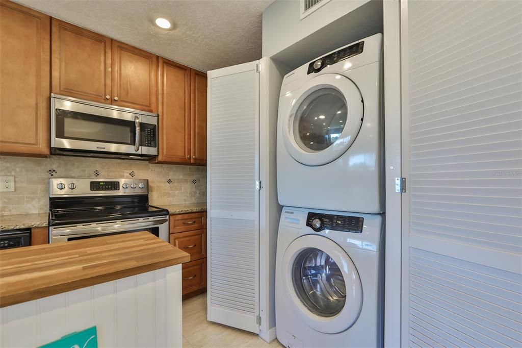 Laundry closet built into the kitchen area with front load washer and dryer included.