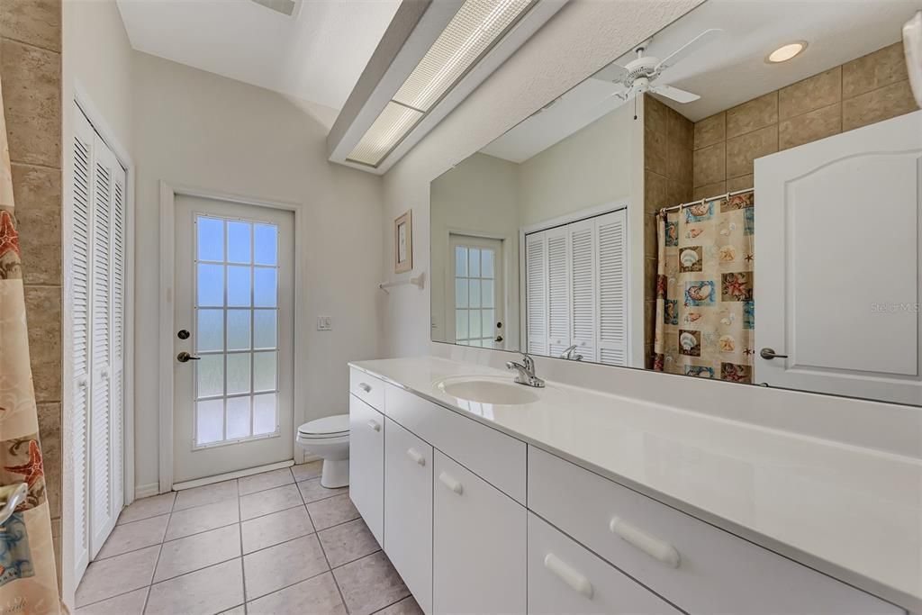 Guest bathroom with tub and shower, large linen closet and a door leading onto the lanai.