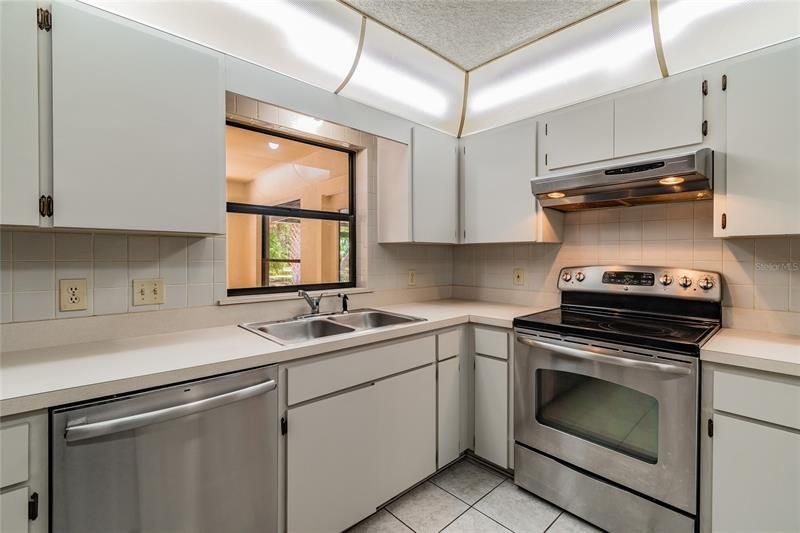 Light and bright Kitchen with double stainless sink, stainless dishwasher, stove, and refrigerator