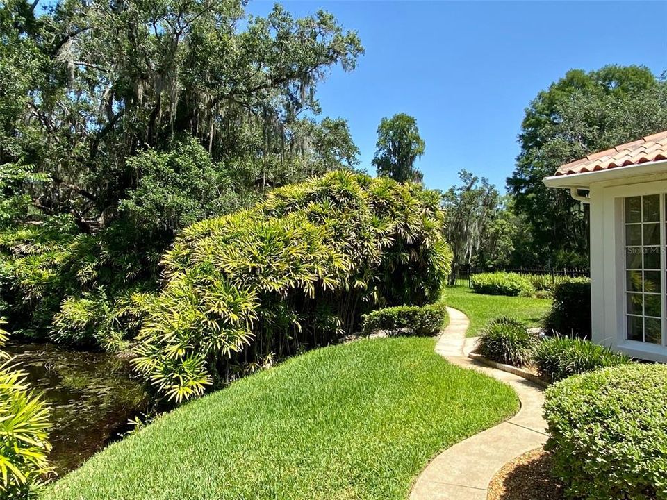 walk way up side with pond and landscaping to the left, river in back