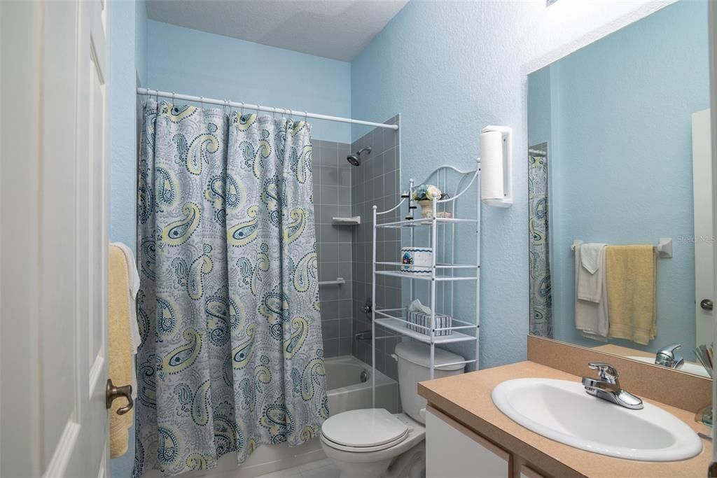 The guest bath has a combination tub and shower with a ceramic tile surround.