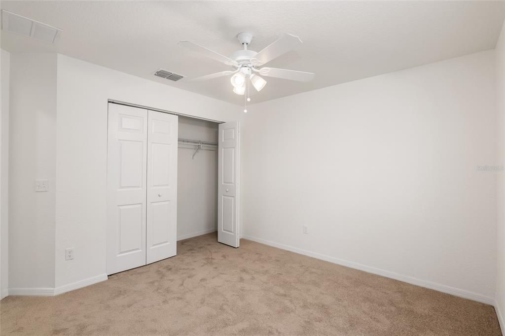 bedroom 2 with ceiling fan abd carpet