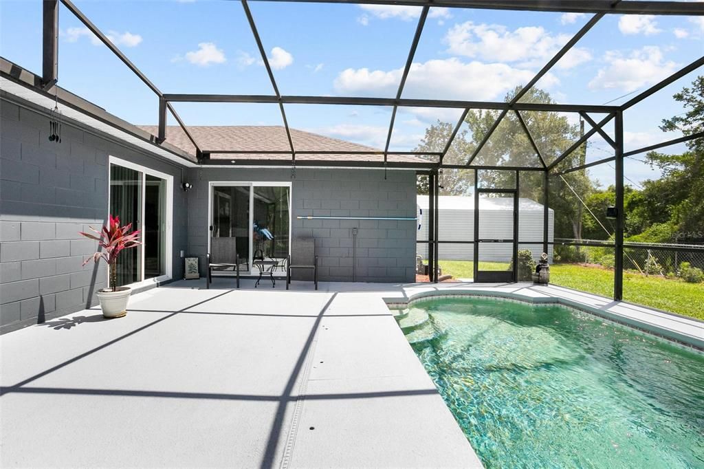 Screened pool enclosure with workshop at right-all inside the fully-fenced back yard.