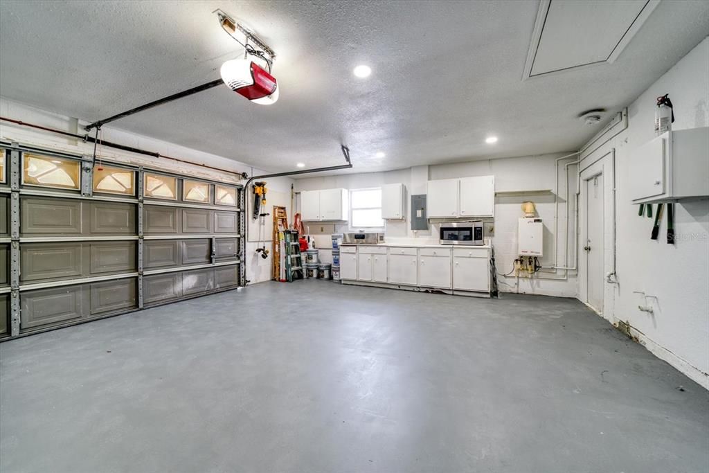 Very well lit 2 car garage with work bench and plenty of cabinets for storage