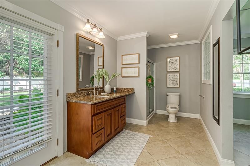 In-law suite's en-suite bathroom has a walk-in tile shower and a tall vanity with granite countertop.