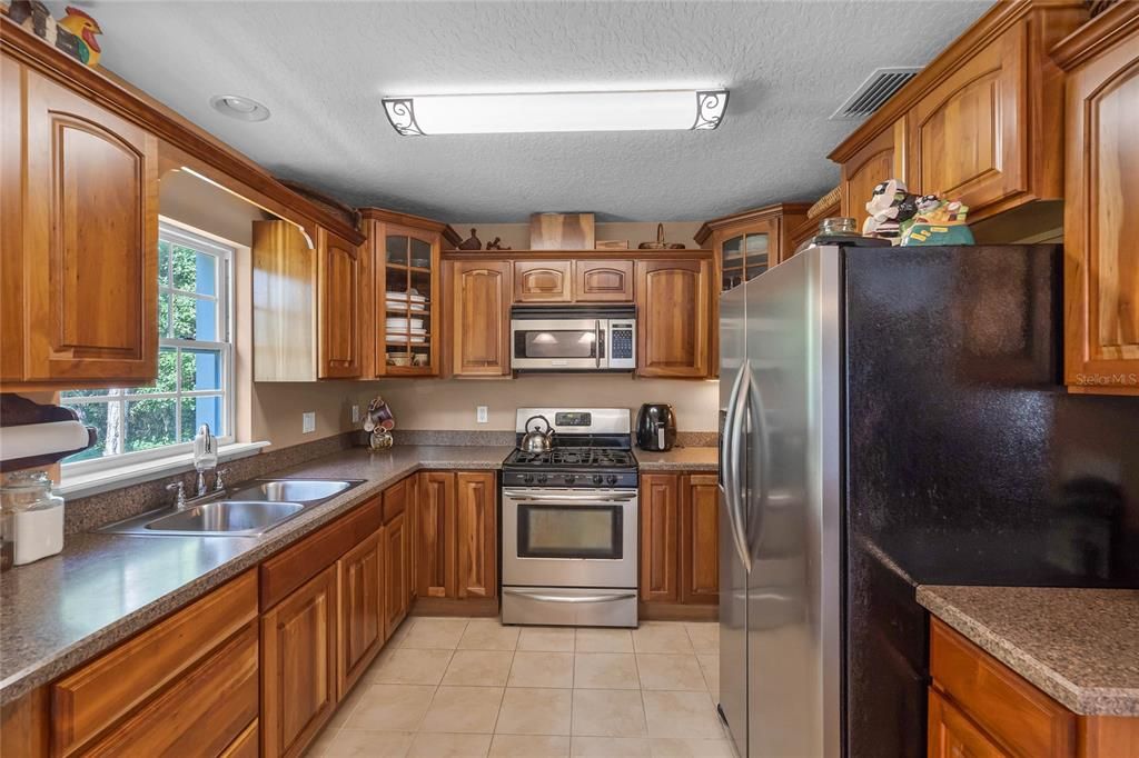 The kitchen is well equipped with a great mix of cabinet and drawer storage, STAINLESS APPLIANCES (including a GAS STOVE!), solid surface counters, closet pantry and a window over the sink for a view of the backyard!