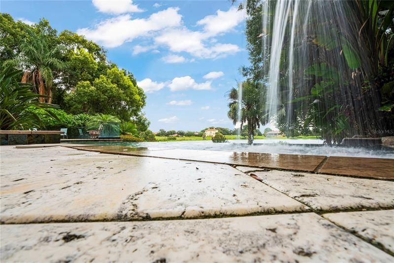 Infinity pool boasts lake backdrop, off travertine deck