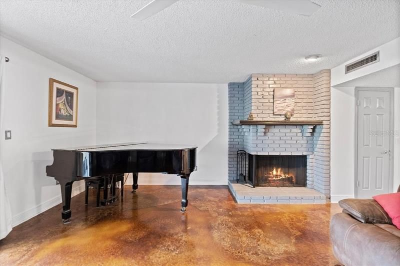 family room with wood burning fireplace and stained concrete flooring.