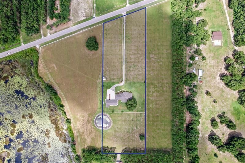 You can tell the property lines almost based on the way the grass is cut. The fenced in area around the house outer fence line is on the property lines. Those points go to the road and to the trees to give the full lot as almost a rectangle. Property line goes through pond.