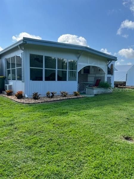 Back of property, lovely landscaping, extra covered patio, view of Florida room