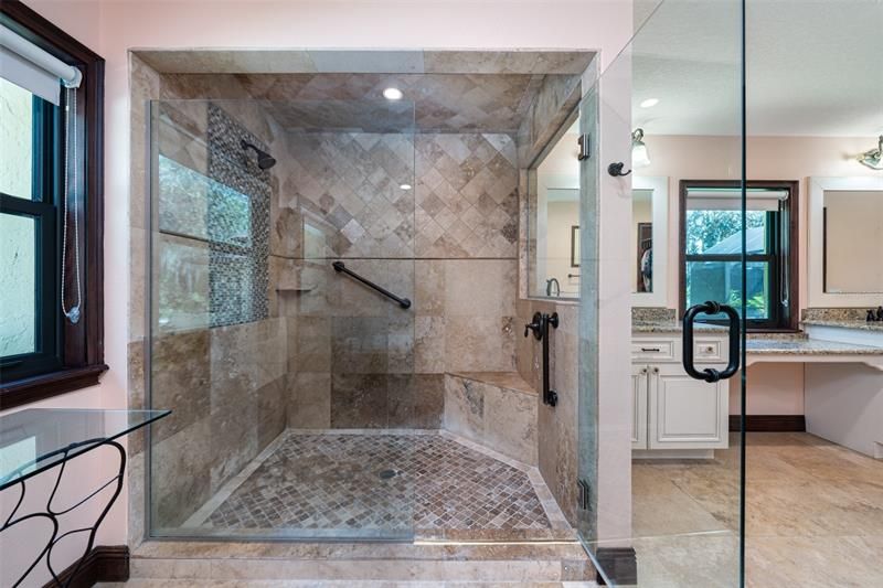 Elegant shower with travertine, linen closet not seen and walk-in-closet.