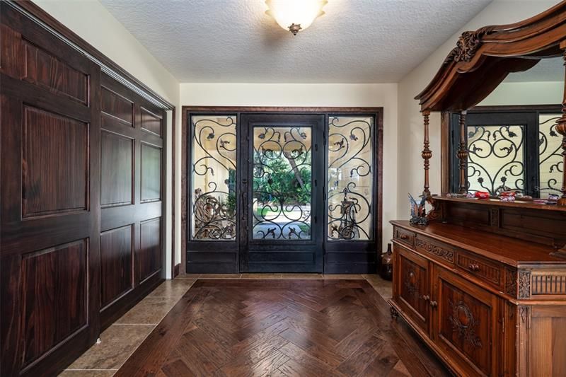 Elegant foyer looking out through the custom iron doors. You can open the glass without having to actually open the door. Inlaid wood was added with all new flooring through out the home. Large hallway closet with custom shelving.