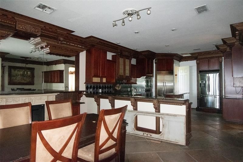 Kitchen w/stainless appliances, can lighting and ornate carved wood features. Dining area off kitchen, mirrored wall and fireplace.