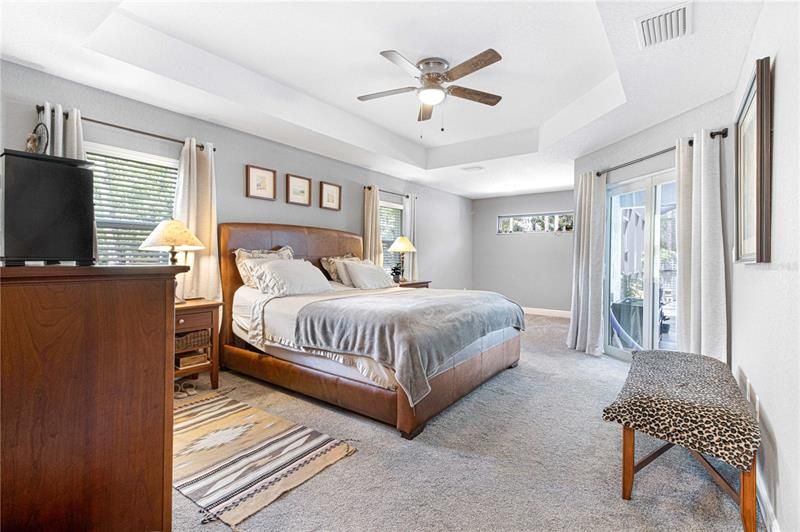 Wonderful master bedroom with tray ceiling, sitting area and doors to the pool