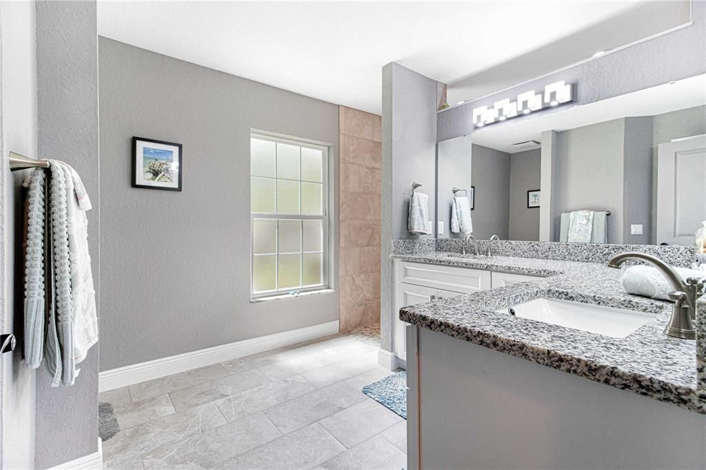 Master bath with L-shaped vanity featuring granite counters and dual sinks