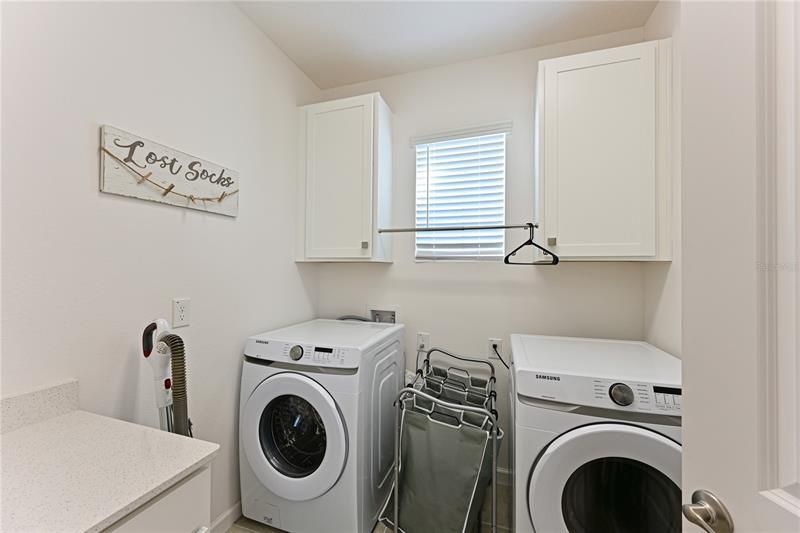 Large Upstairs laundry room with cabinets and a place to hang clothes.