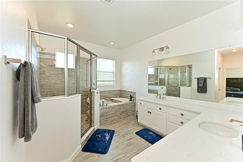 Master Bathroom with walk-in shower, garden tub, dual sinks and upgraded quartz counters and upgraded ceramic plank tile floor