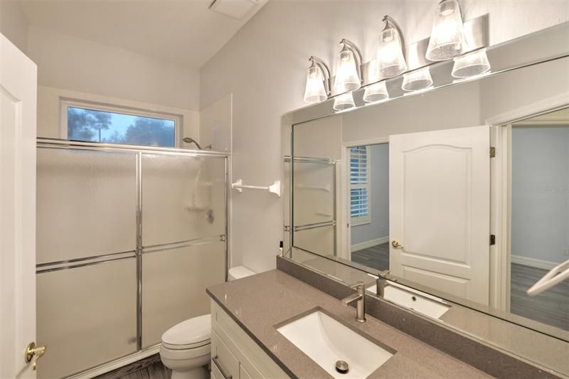 Guest bath off guest bedroom with pocket door makes it a private suite. Quartz counters with walk in shower.