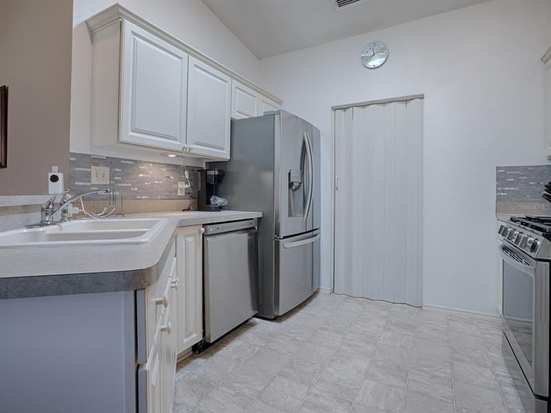 LOVELY KITCHEN WITH NEWER LG STAINLESS APPLIANCES, WHITE BAY CABINETS WITH CROWN MOLDING AND HARDWARE AND MOSAIC TILE BACKSPLASH.