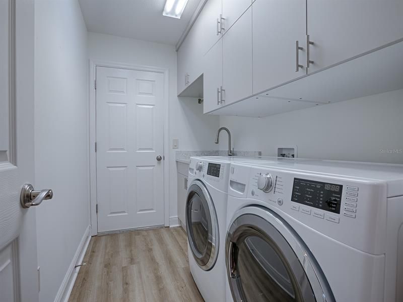 LAUNDRY ROOM WITH FRONT-LOAD WASHER AND DRYER, QUARTZ COUNTERS, SET-TUB, AND LOTS OF ADDITIONAL CABINETS FOR STORAGE, AND SOLAR TUBE FOR NATURAL LIGHT.  THE DOOR LEADS TO YOUR OVERSIZED GARAGE.