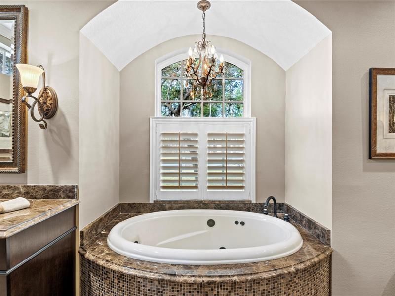 Close up of the Soaking Tub w/ Matching Granite Tub Deck and an Overhead Chandelier